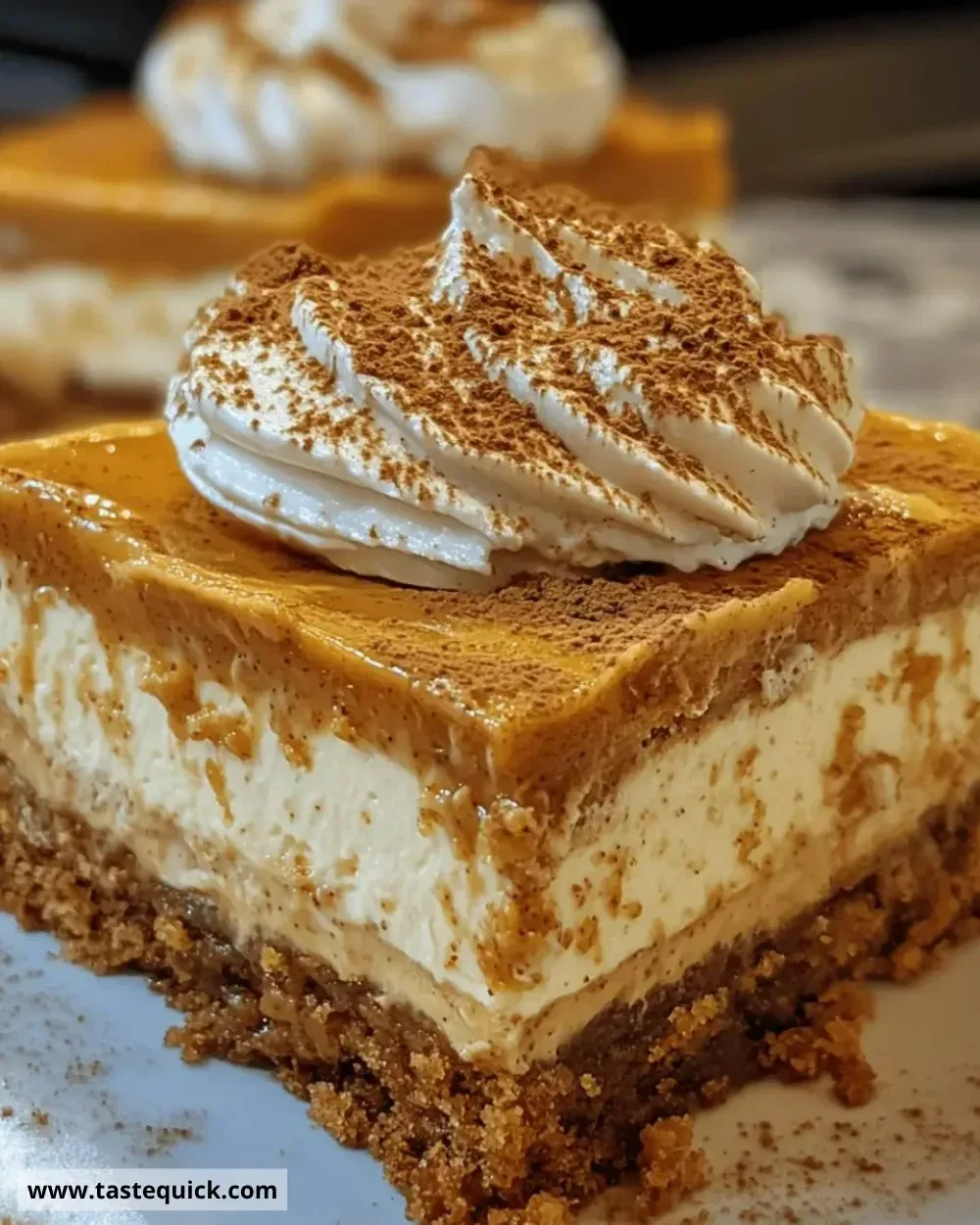 Delicious pumpkin spice cheesecake bars topped with whipped cream and autumn spices.