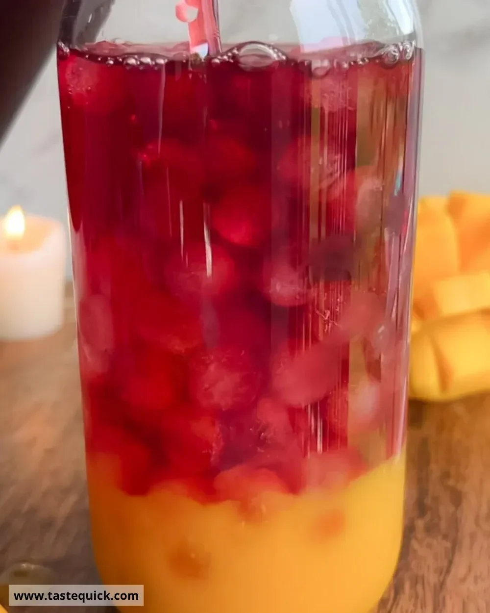 A refreshing glass of Mango Hibiscus Iced Tea garnished with fresh mango slices and hibiscus flowers.
