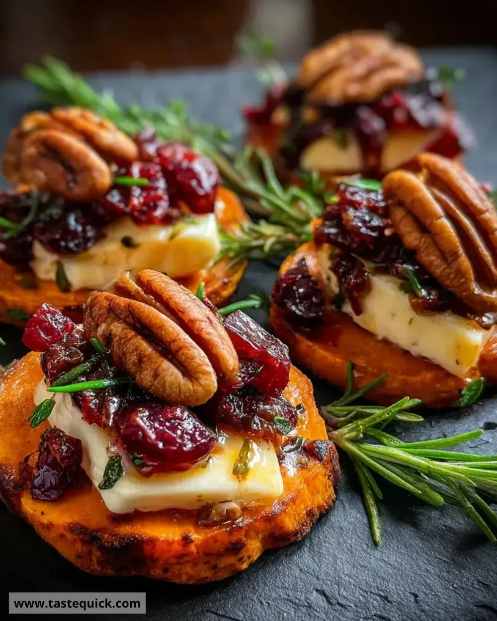 Sweet potato rounds topped with brie cheese, cranberry, and pecans