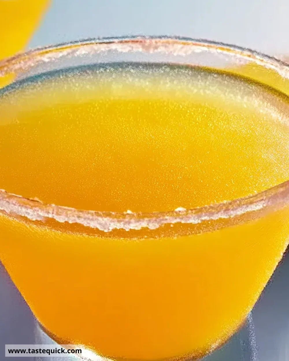 Refreshing Tang-tini cocktail with a vibrant orange hue and citrus garnish.