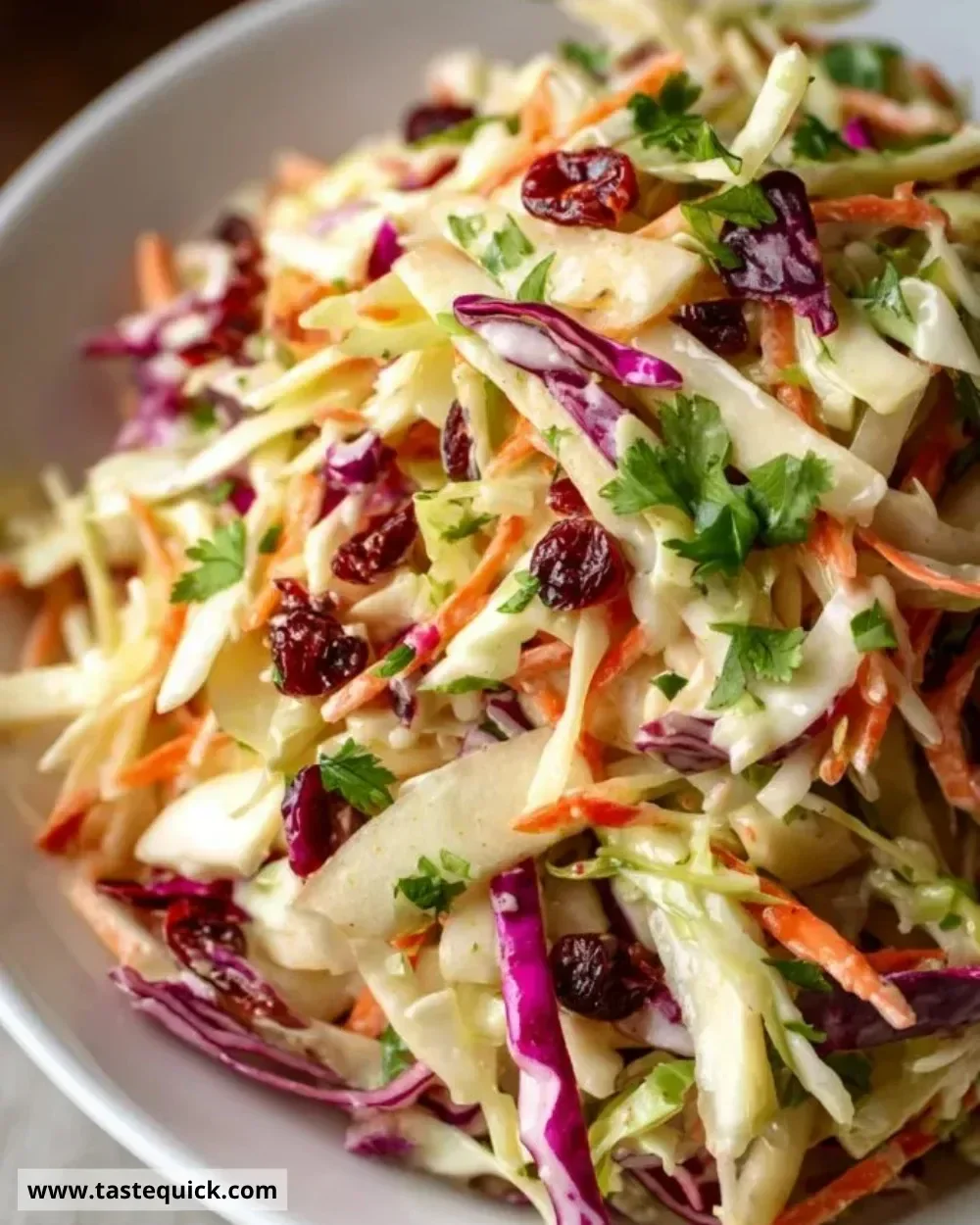Zesty apple cranberry coleslaw with fresh apples and cranberries served in a bowl.