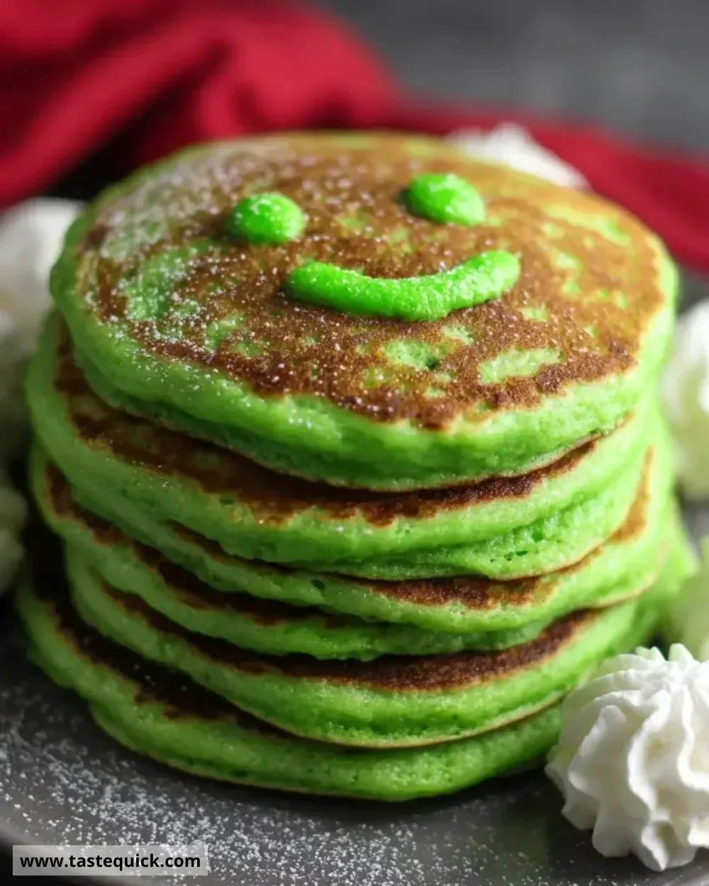 Plate of Grinch Pancakes topped with red and green syrup and whipped cream