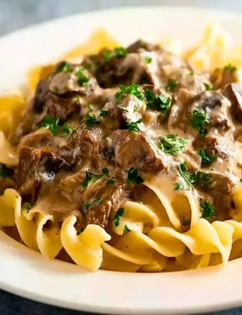 Slow cooker beef stroganoff served in a bowl with garnishes
