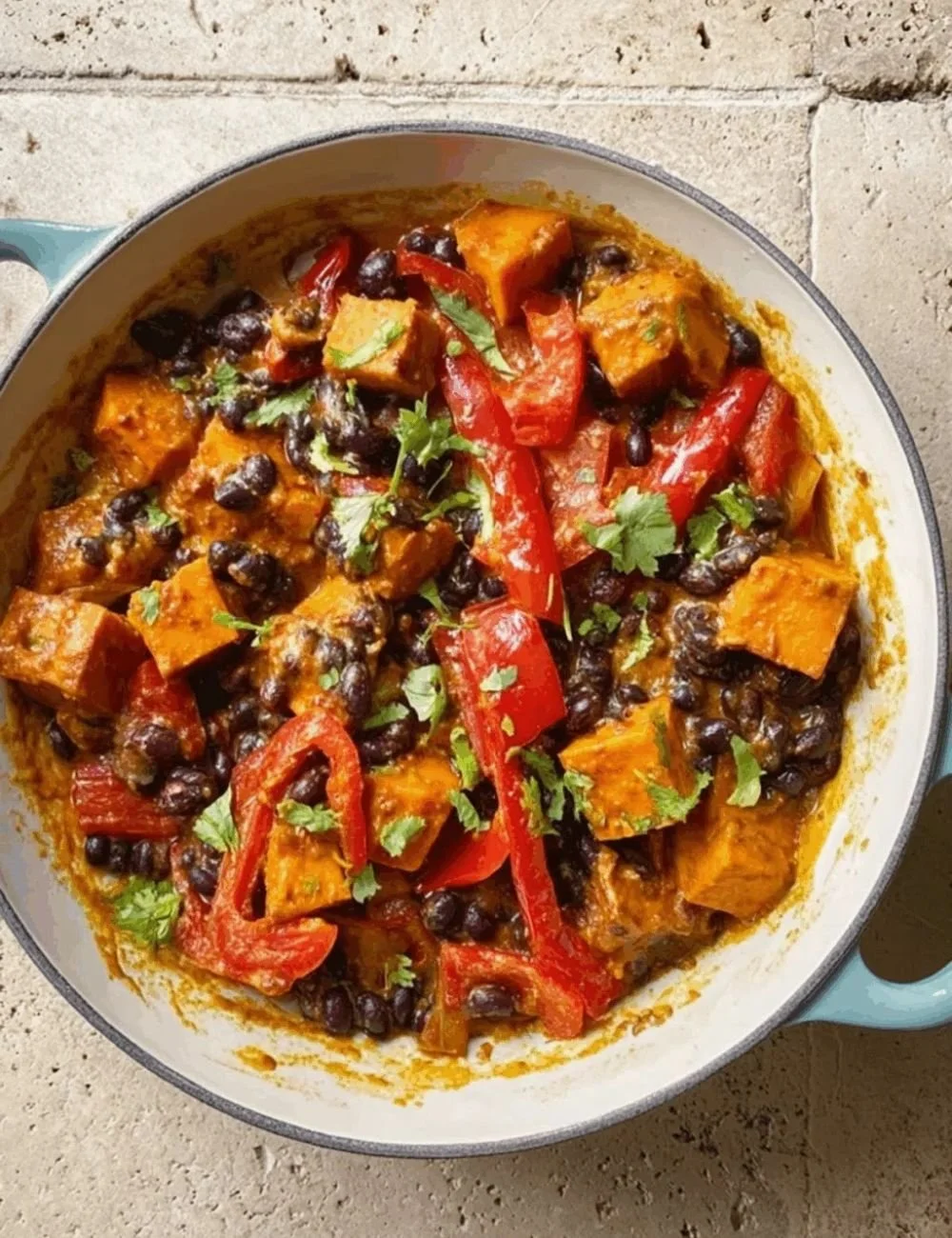 Jerk sweet potato and black bean curry served in a bowl with fresh herbs