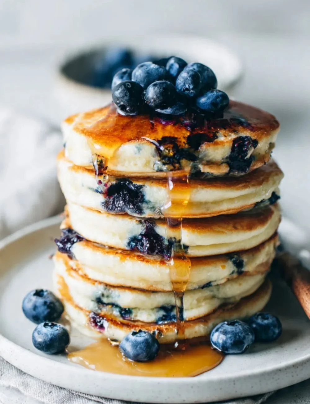 Delicious blueberry pancakes stacked with fresh blueberries and syrup on top.