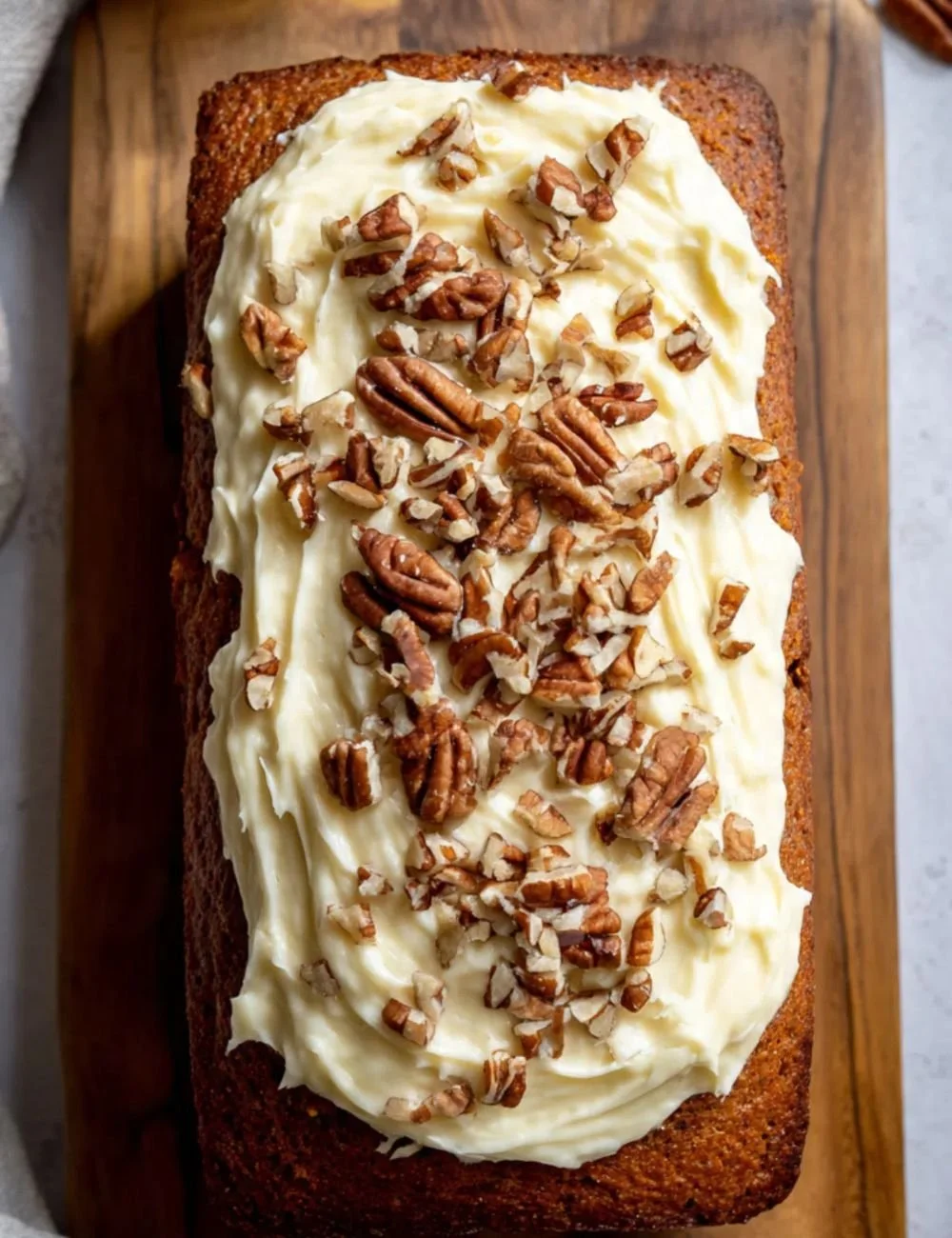 Homemade carrot cake loaf with cream cheese frosting on a wooden table