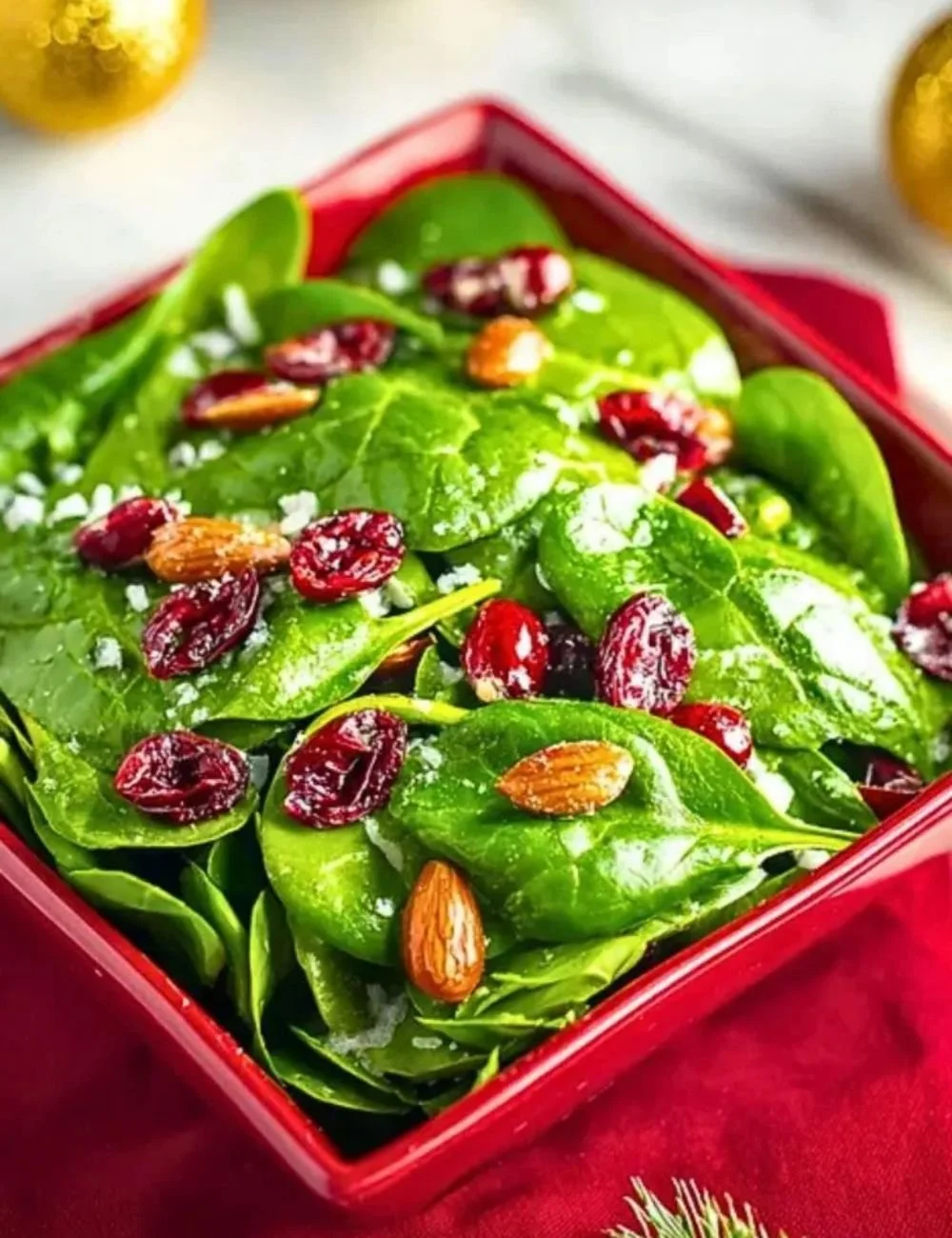 Christmas Cranberry Spinach Salad with nuts and dressing in a festive bowl