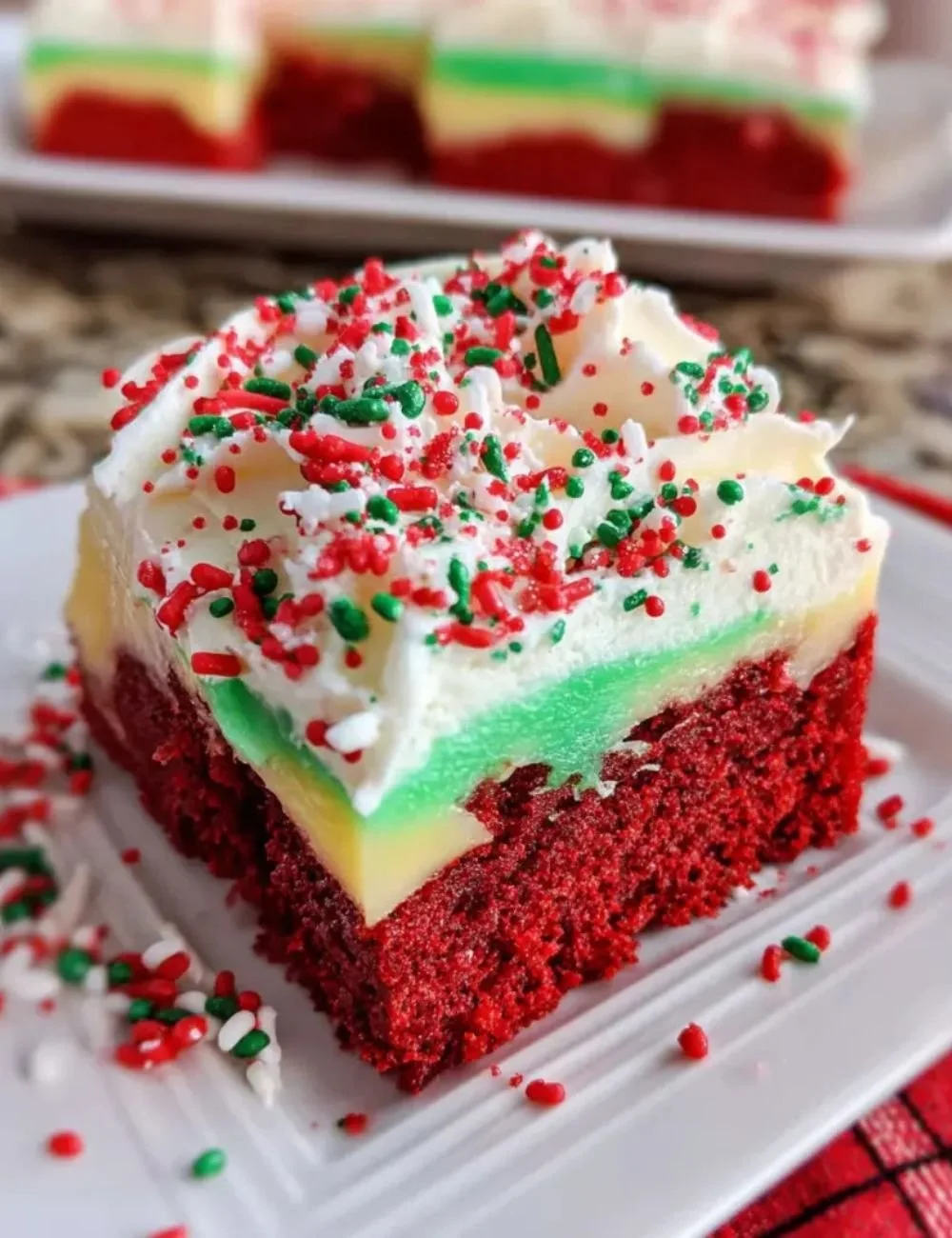 Christmas Red Velvet Poke Cake topped with cream cheese frosting and festive sprinkles