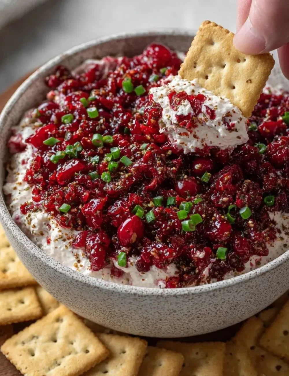 Cranberry Jalapeño Cream Cheese Dip served in a bowl with crackers around it