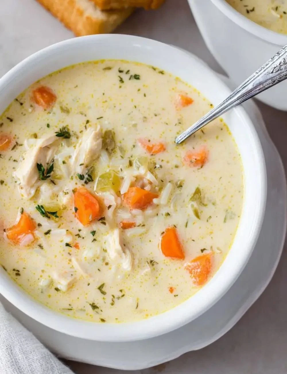 Bowl of creamy chicken rice soup garnished with herbs