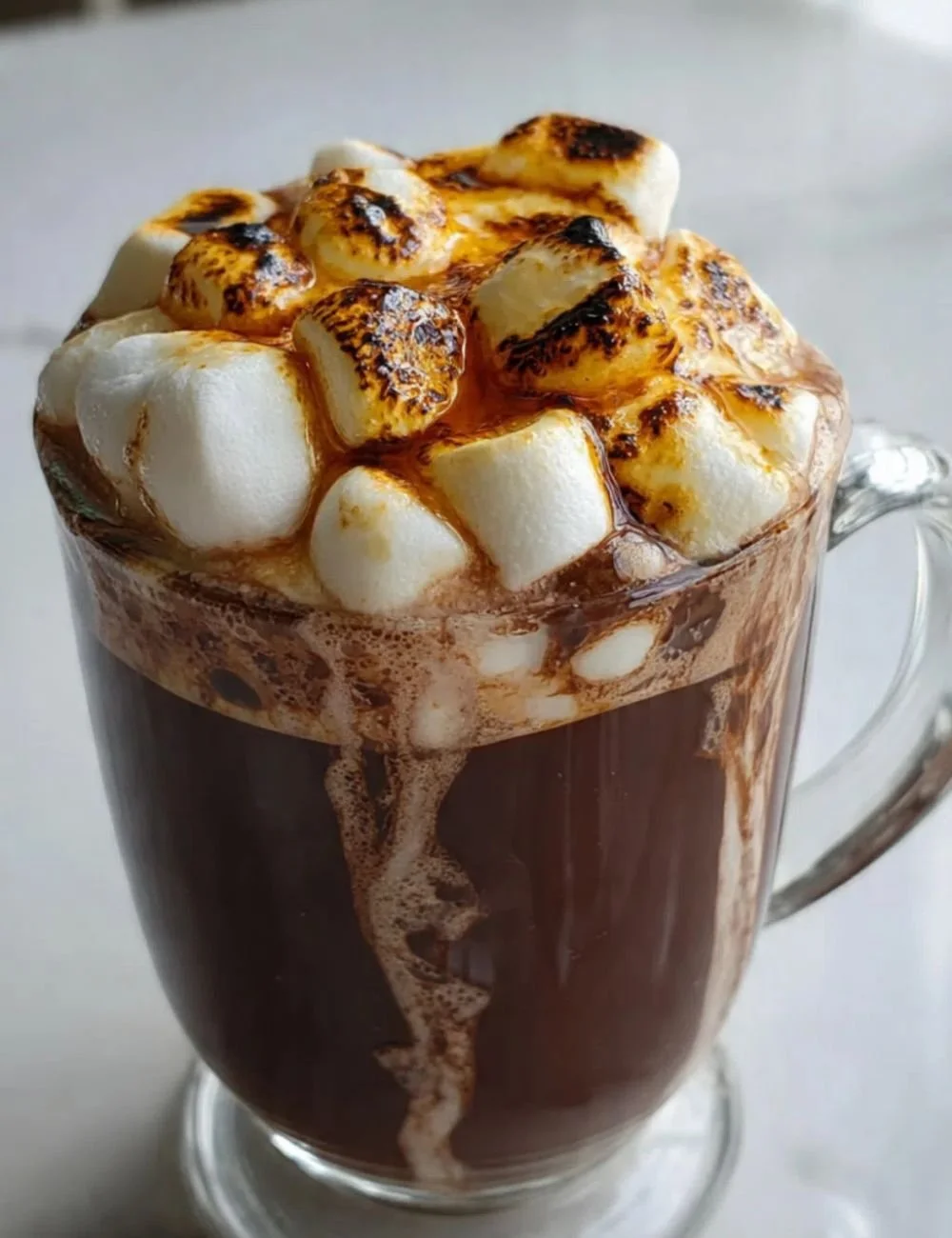 Creamy hot cocoa served with torched marshmallows in a cozy mug