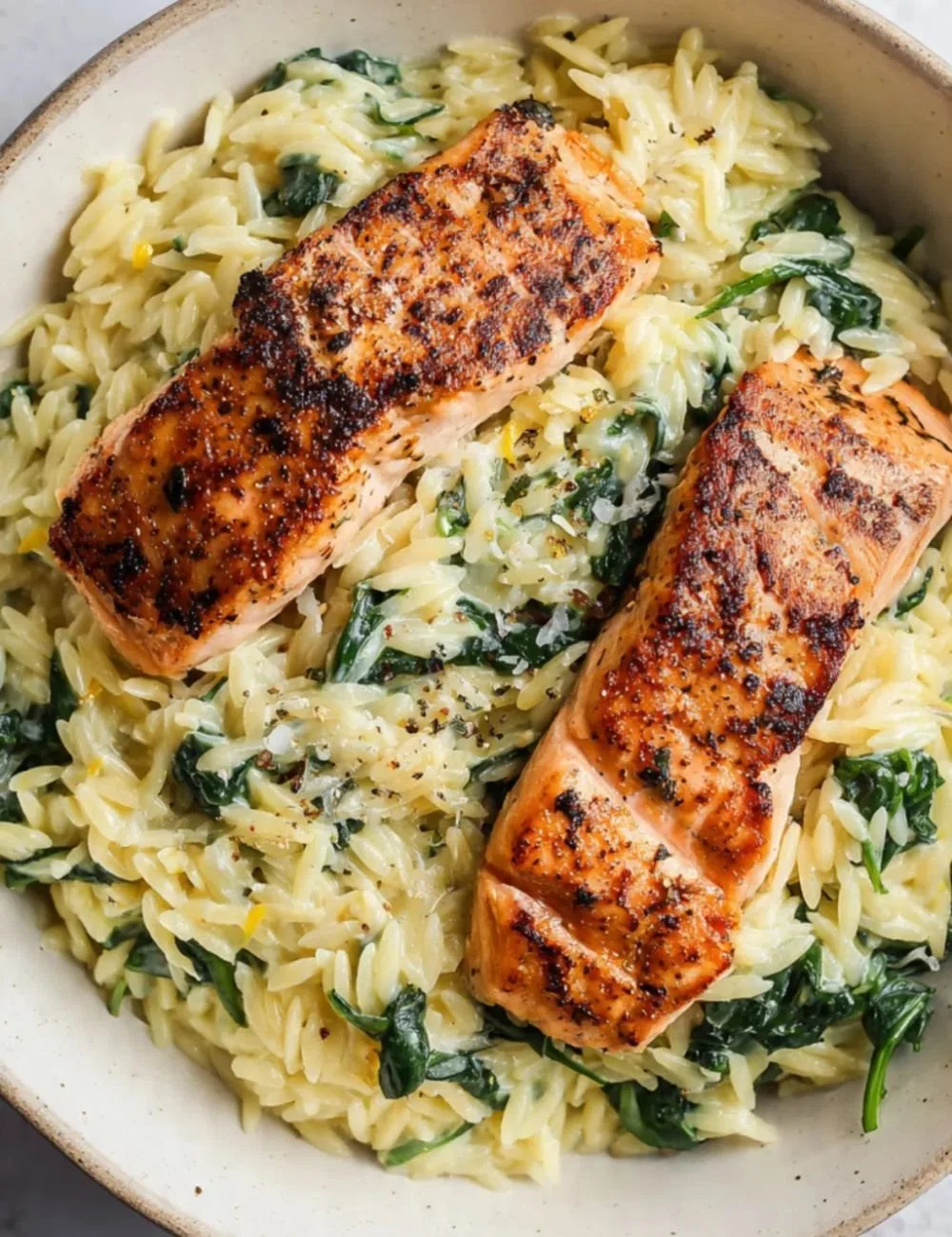 Creamy lemony orzo with seared salmon served on a plate.