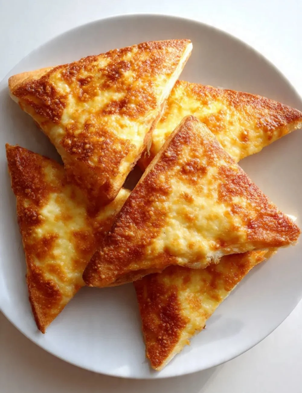 Delicious pizza triangles served on a plate with toppings and fresh herbs.