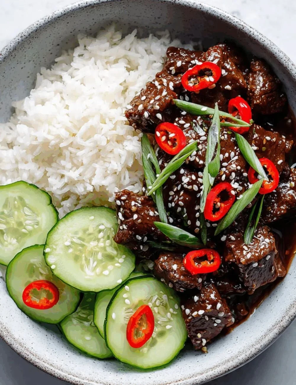 Plate of Sticky Sesame Beef garnished with crunchy cucumbers