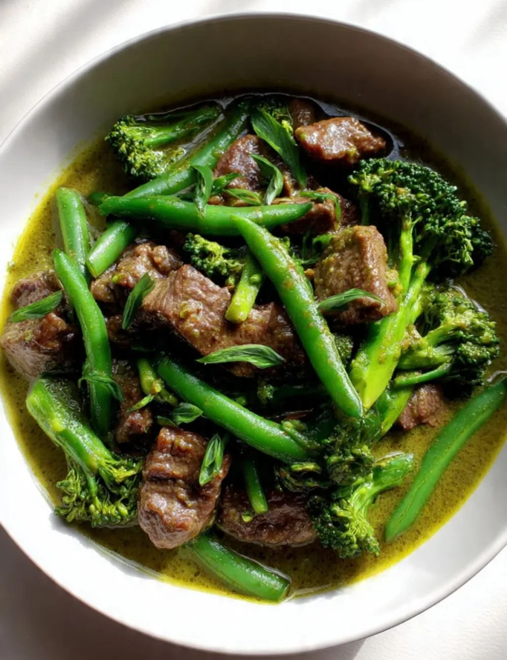 Bowl of braised beef curry in spicy green sauce with herbs