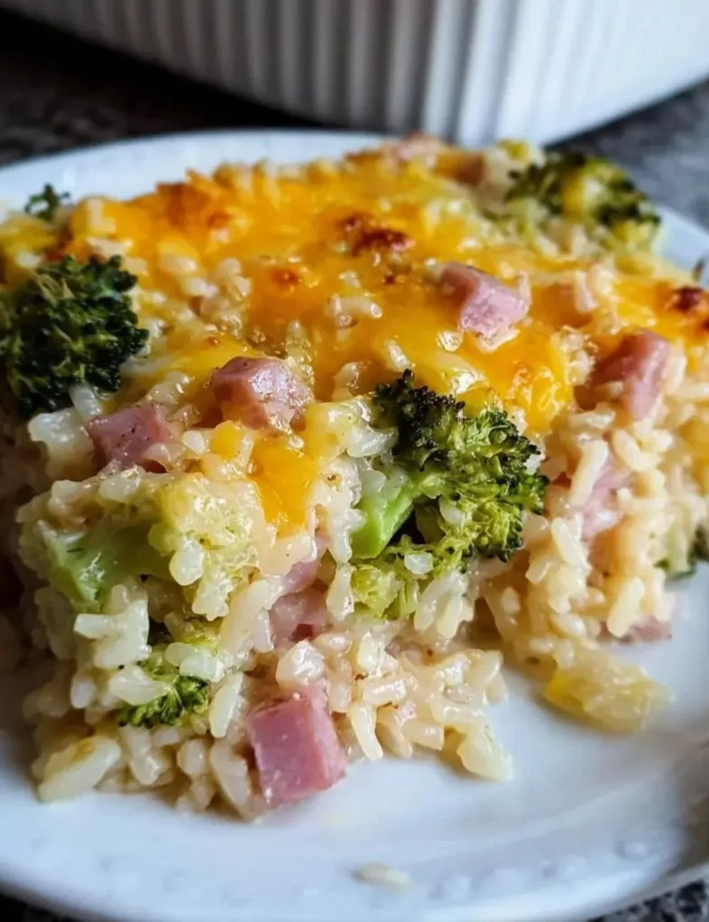 Baked dish featuring broccoli, ham, and rice in a creamy casserole