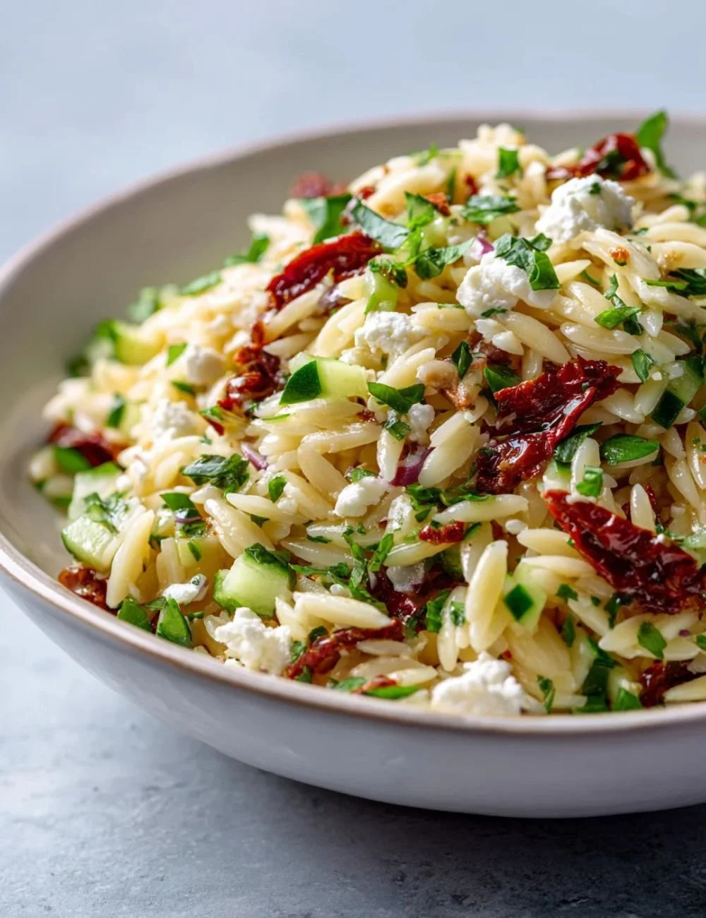 Delicious homemade orzo pasta salad with colorful vegetables and herbs.