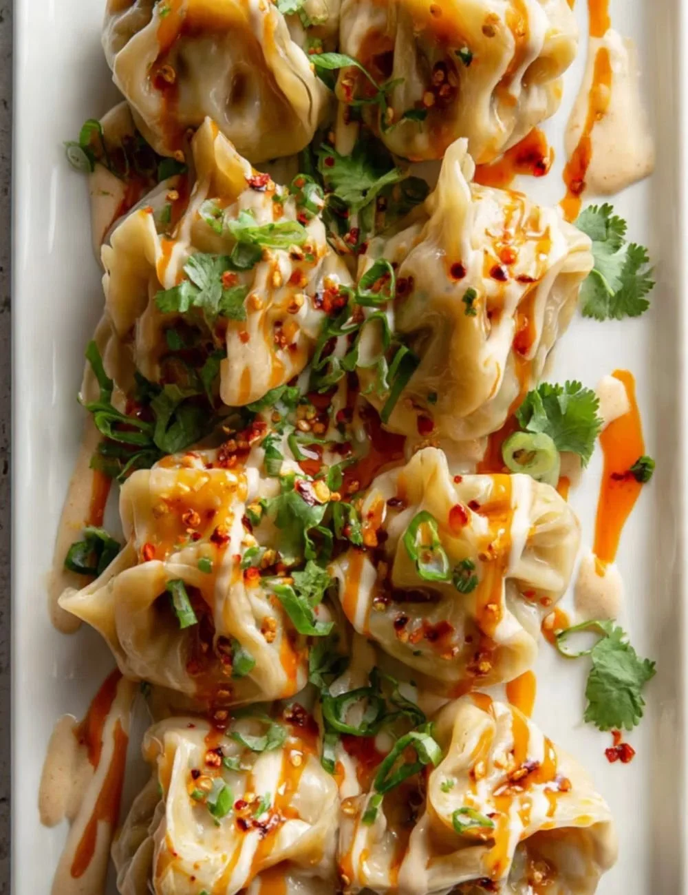 Juicy chicken dumplings drizzled with tahini lime sauce, ready to serve.