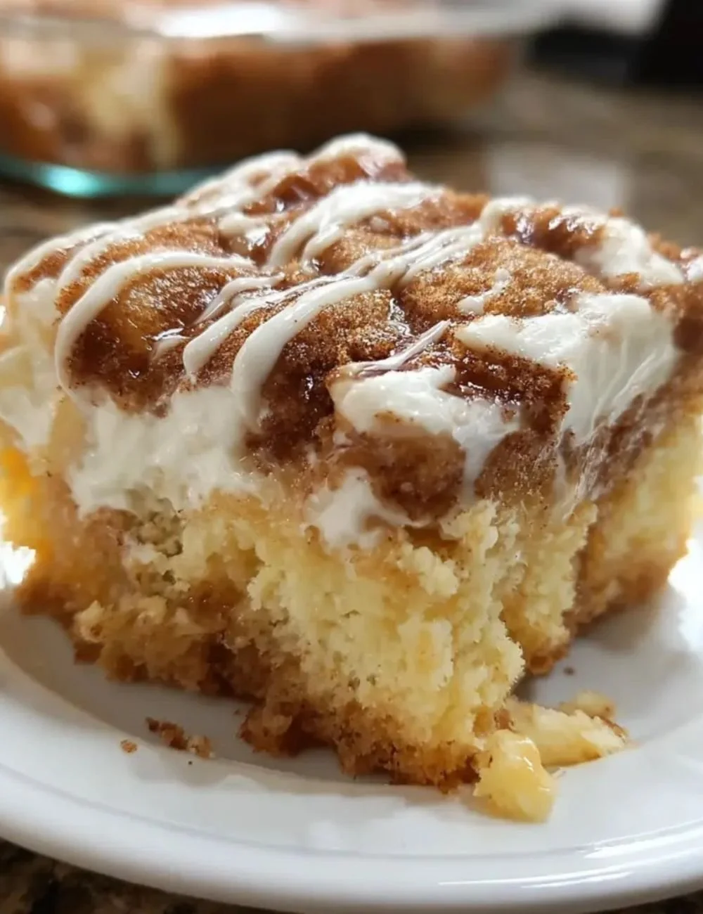 Delicious cinnamon roll poke cake topped with icing and cinnamon sugar.