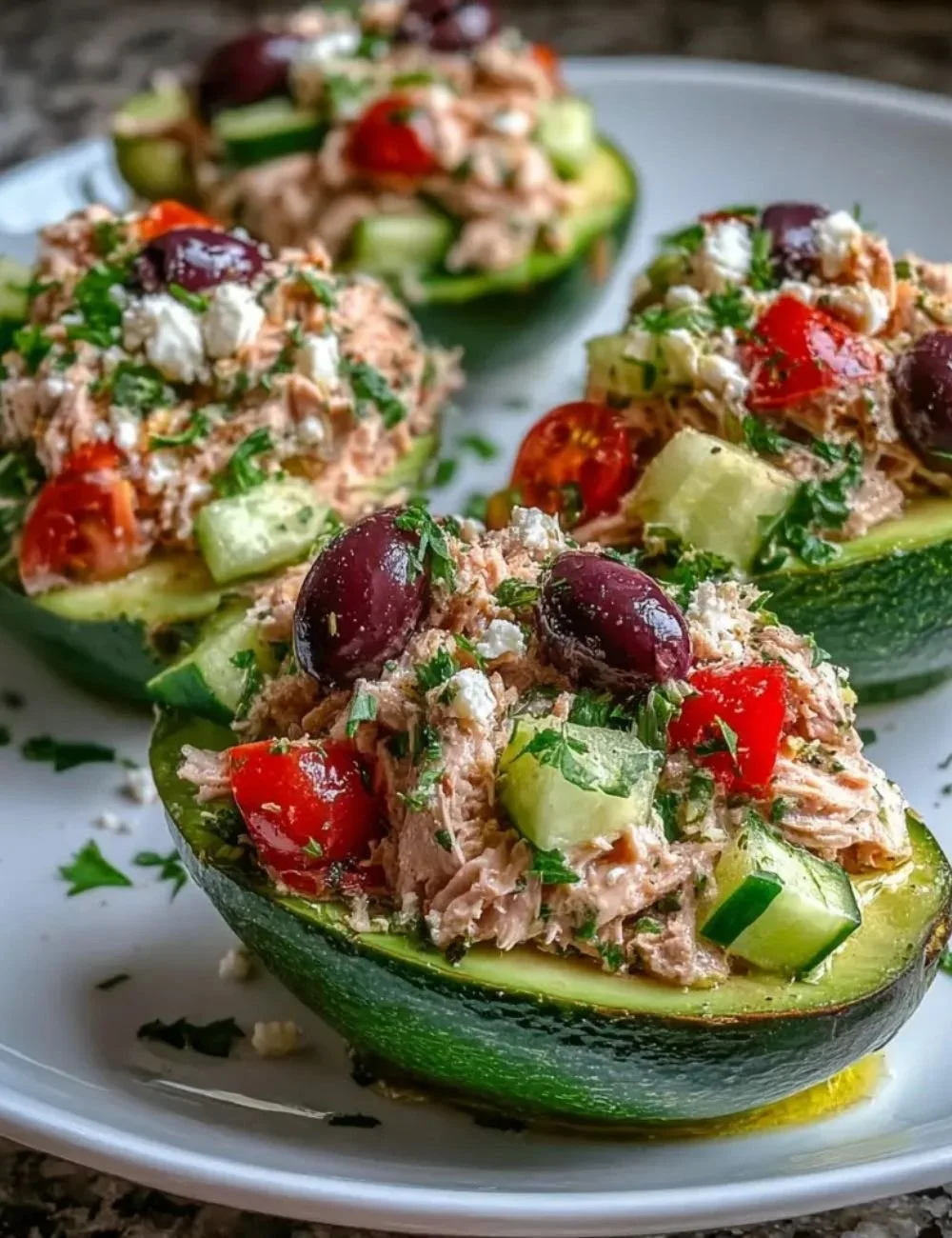 Mediterranean tuna salad stuffed avocados served on a plate.