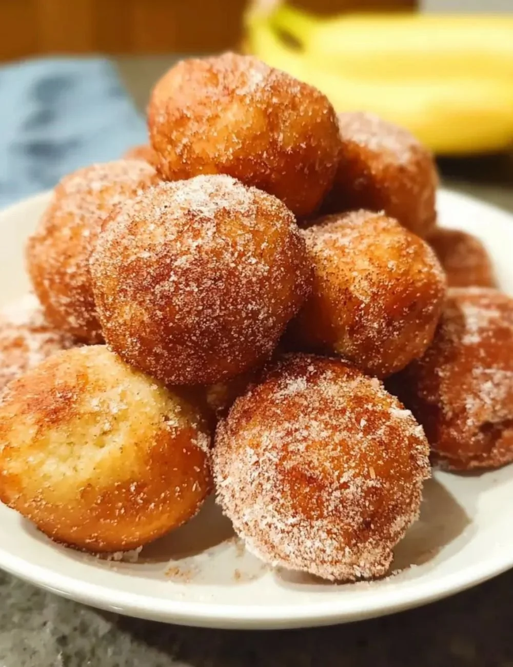 Plate of fluffy Banana Donut Holes dusted with powdered sugar
