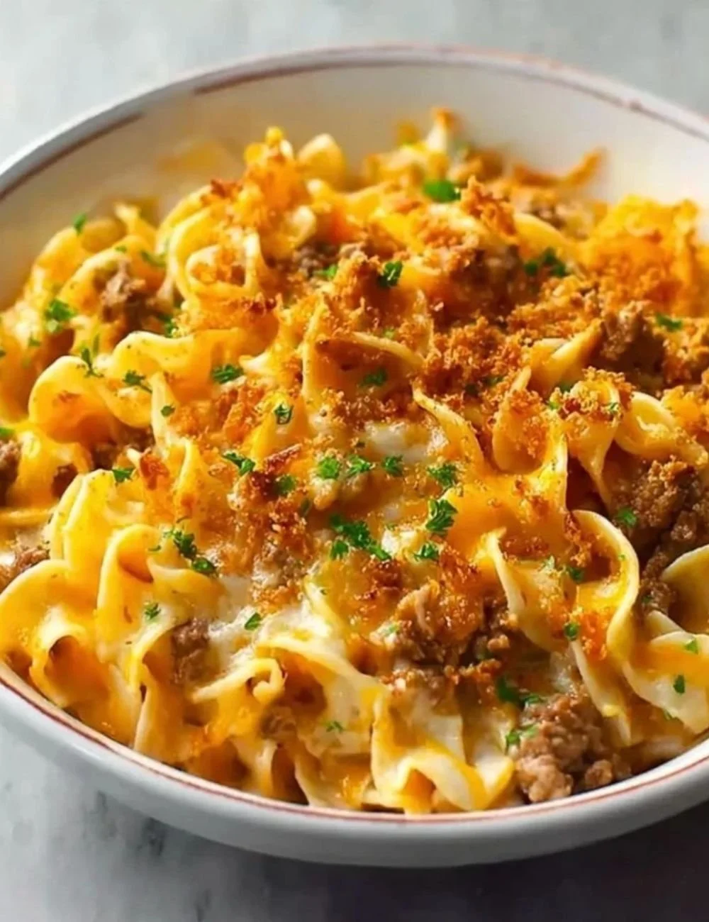 Cheesy Beef and Noodle Casserole topped with melted cheese and herbs