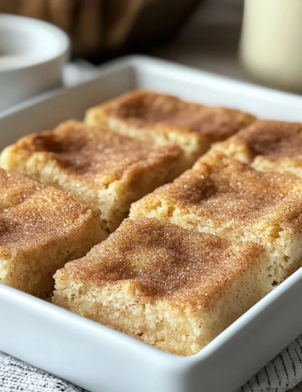 Chewy snickerdoodle cookie bars topped with cinnamon sugar on a plate