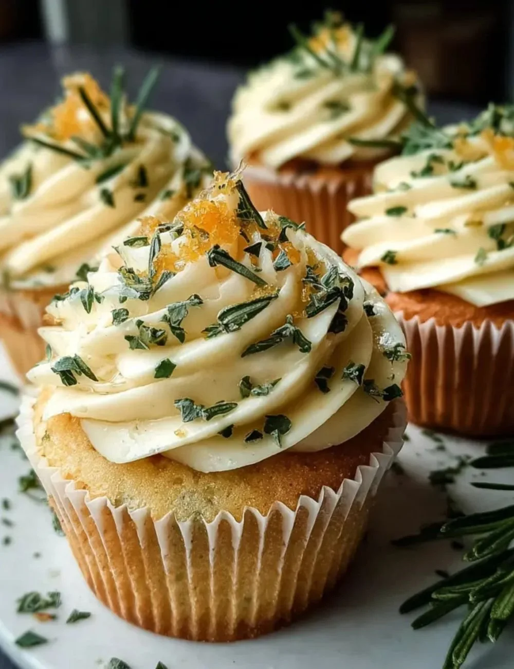 Lemon Thyme Rosemary Cupcakes garnished with fresh herbs and lemon zest