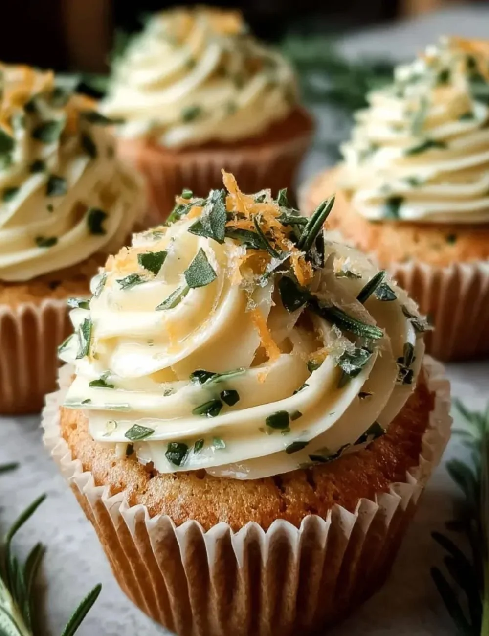 Lemon Thyme Rosemary Cupcakes topped with lemon zest and fresh herbs